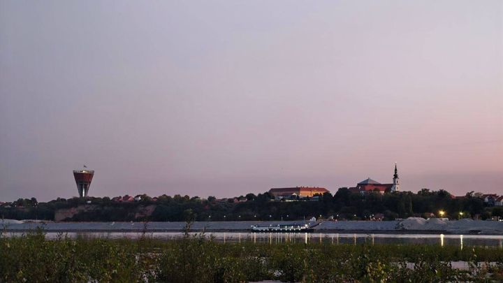 Vukovar across the Danube at dusk: the water tower on the left, a church spire on the hill on the right