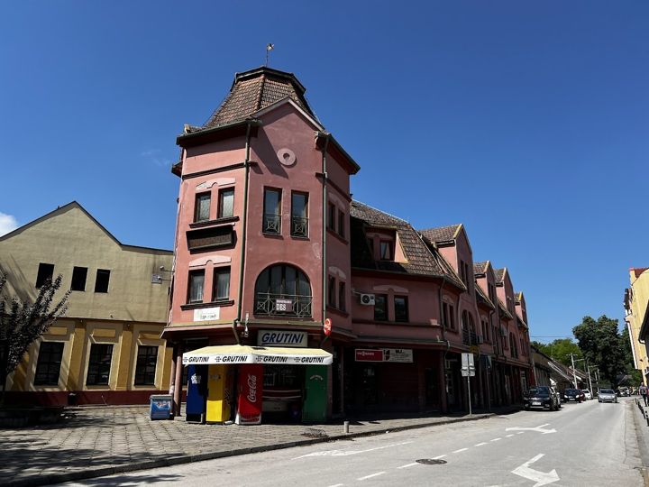 A pink corner house with a tower-like roof and a kiosk in Sombor