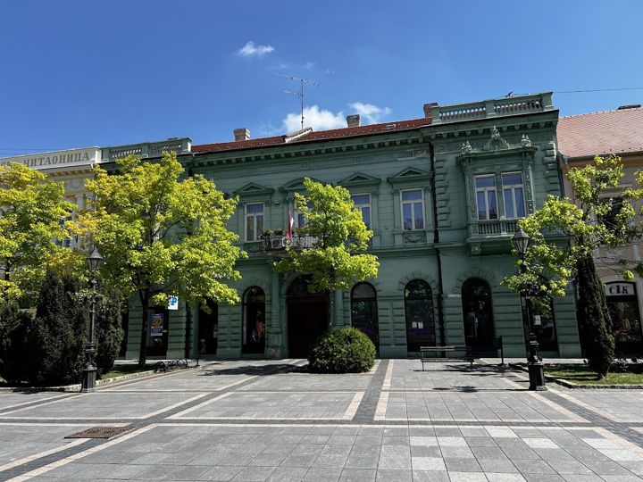 A green eclectic palace next to the Serbian Reading Room (its sign ЧИТАОНИЦА on the left) in the centre of Sombor