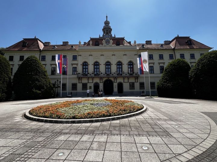 The former Bács-Bodrog County Hall (Županija) in Sombor with flags and a round flowerbed in front